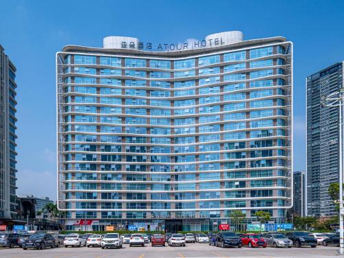 Un edificio alto con coches aparcados en un estacionamiento. en Atour Hotel Foshan Shunde Happy Coast, en Shunde