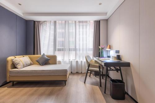 a living room with a couch and a desk and a window at Atour X Hotel Shenzhen Luohu Sungang Baoneng Center in Shenzhen