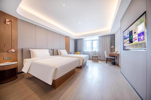 una camera d'albergo con due letti e una TV a schermo piatto di Atour X Hotel Beijing Yonghe Temple Hepingli a Pechino