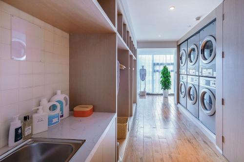 a laundry room with a sink and washing machines at Atour Hotel Kunming South High Speed ​​Railway Station University Town in Kunming