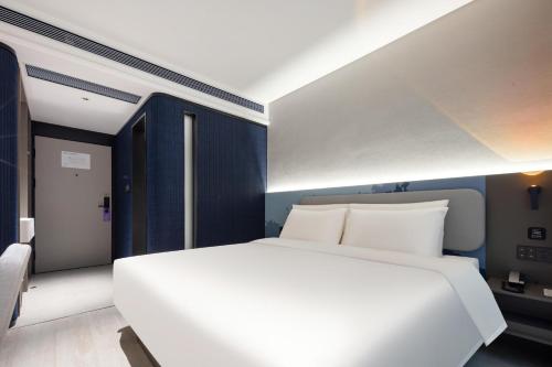 1 dormitorio con 1 cama blanca y paredes azules en Atour Light Hotel Shenzhen Nanshan Raffles City Plaza en Shenzhen