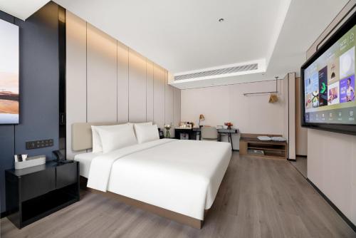 a bedroom with a white bed and a flat screen tv at Atour Hotel Xi'an Bell Tower Dacha City Metro Station in Xi'an