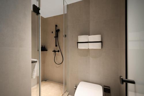 a bathroom with a shower with a toilet and towels at Atour Light Hotel Chongqing Yuzhong Daping Metro Station in Chongqing