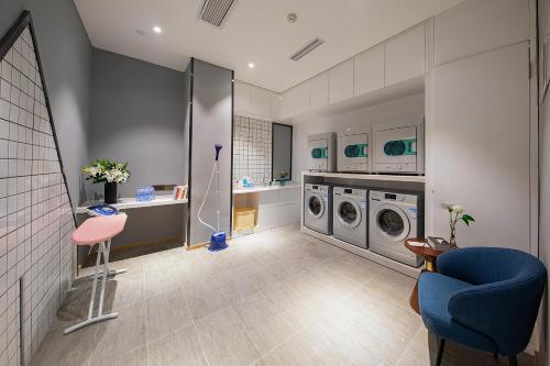 a bathroom with two washing machines and a blue chair at Atour Hotel Chengdu Chunxi Road Tianfu Square Subway Station in Chengdu
