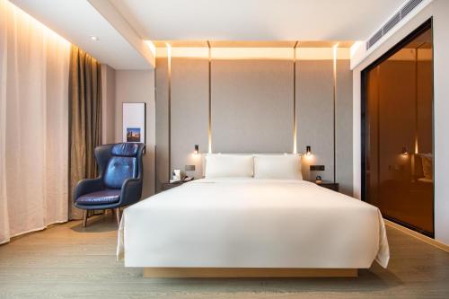 - une chambre avec un grand lit blanc et une chaise dans l'établissement Atour Hotel Shenzhen Guangming New City, à Shenzhen