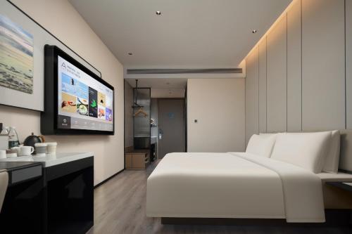 a bedroom with a white bed and a flat screen tv at Atour Hotel Xiamen Xiang'an Torch Industrial Park in Xiang'an