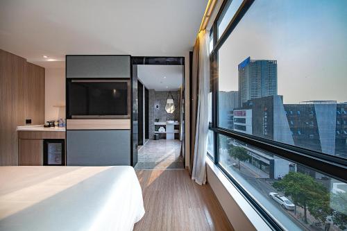 a bedroom with a large window with a view of a city at Atour Hotel Shenzhen Baoan Xixiang in Bao'an