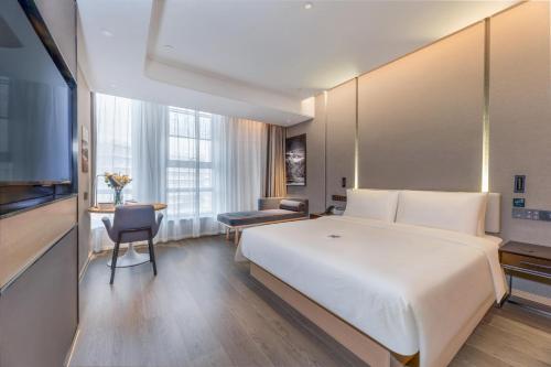 Una habitación de hotel con una gran cama blanca y un escritorio. en Atour Hotel Zhijiang Bridge, en Hangzhou