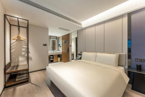 a bedroom with a large white bed and a bathroom at Atour Hotel Shanghai Xintiandi Metro Station in Shanghai