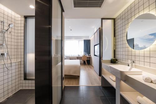 a hotel bathroom with a sink and a bed at Atour Light Hotel Temple of Heaven in Beijing
