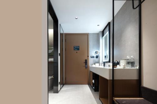 a bathroom with a sink and a door to a room at Atour Hotel Xiamen Xiang'an Torch Industrial Park in Xiang'an