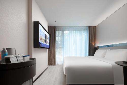 a hotel room with a white bed and a flat screen tv at Atour Light Hotel Shenzhen Nanshan Nanyou Clothing City in Shenzhen