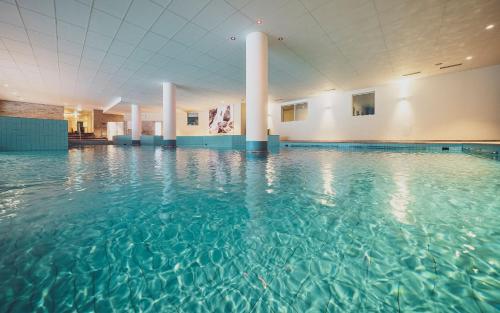 a swimming pool with blue water in a building at Mountain Plaza Hotel in Davos