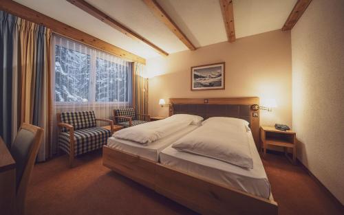 ein Schlafzimmer mit einem Bett, einem Stuhl und einem Fenster in der Unterkunft Mountain Plaza Hotel in Davos