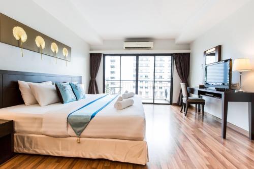 a bedroom with a bed and a desk with a television at Fifth Pattaya Jomtien By Shiwalai Int in Jomtien Beach