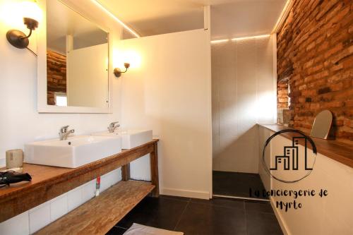 une salle de bain avec deux lavabos et un miroir dans l'établissement Le Quinze, à Albi