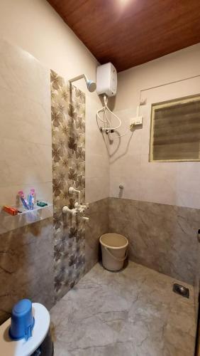 a bathroom with a shower and a toilet in it at Vighnaharta Homestay in Ganpatipule