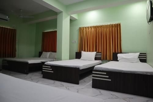 two beds in a room with green walls at Hotel Saan in Baharampur