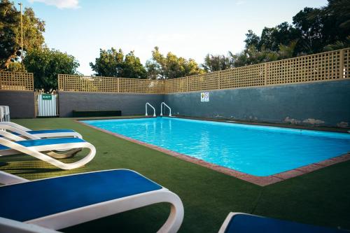 a swimming pool with lounge chairs next to it at Capricorn Holiday Park in Carnarvon