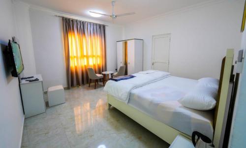1 dormitorio con cama, mesa y TV en نسائم صلاله NassayemSalalah, en Salalah