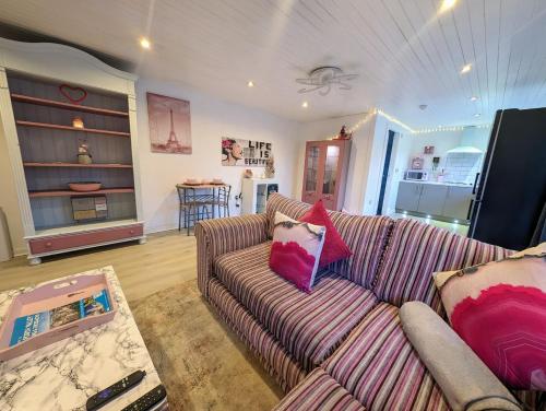 a living room with a striped couch and a kitchen at The Cabin in Bonnybridge
