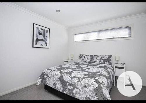 a white bedroom with a bed and a window at Modern cottage central location in Phillip