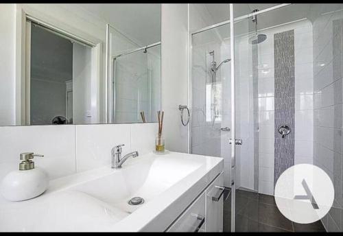 a white bathroom with a sink and a shower at Modern cottage central location in Phillip