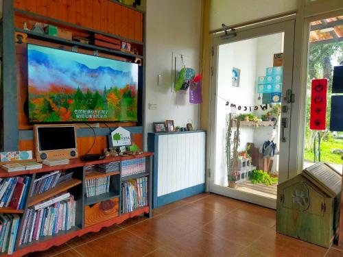 a room with a large screen tv and a book shelf at Mei Shiou B&B in Dongshan