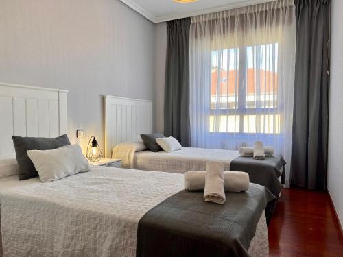 1 Schlafzimmer mit 2 Betten und einem Fenster in der Unterkunft Apartamento Dama Suances in Suances