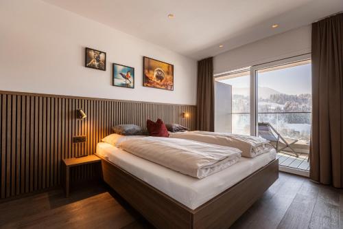 een slaapkamer met een groot bed en een groot raam bij Brixental Suites Hopfgarten by ALPS RESORTS in Hopfgarten im Brixental