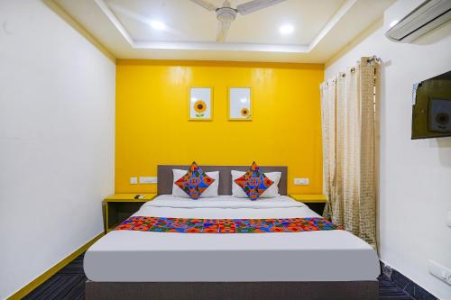 um quarto com uma cama com uma parede amarela em FabExpress Luxury Inn em Hyderabad