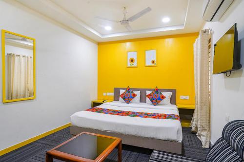 um quarto com uma cama e uma parede amarela em FabExpress Luxury Inn em Hyderabad