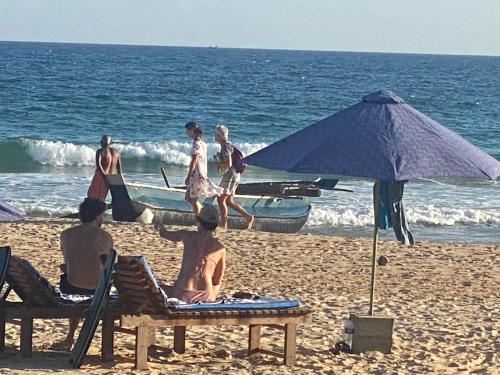 a group of people sitting on the beach at Talalla Bay Beach in Talalla