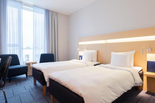 a hotel room with two beds and a chair at Best Western Plus Park City Malmö in Malmö