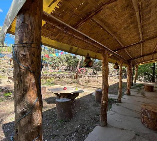 a wooden pavilion with a picnic table in a park at Glampinn Woods in Nainital