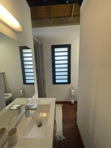 a white bathroom with a sink and two windows at La tête dans les airs, les pieds dans l’eau! in Saint-Denis