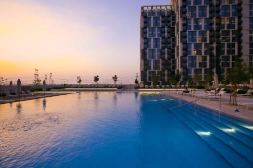 a large swimming pool in front of a tall building at First Class 1BR Apartment in Dubai Hills - next to Dubai Hills Mall in Dubai