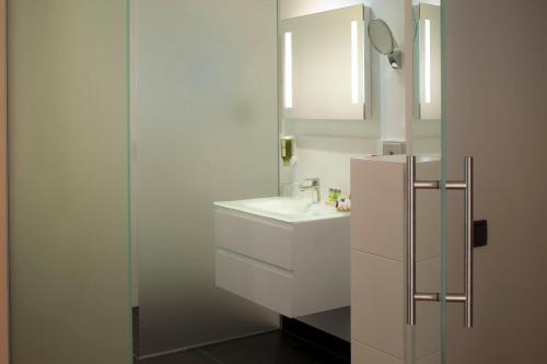 a white bathroom with a sink and a mirror at Hotel Le Pavillon 7 in Obernai