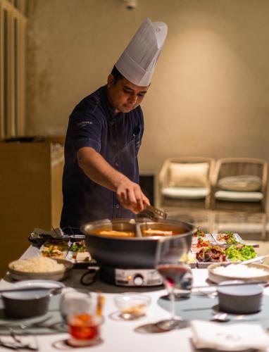 a man in a chefs hat preparing food in a wok at The Westin Goa in Vagator