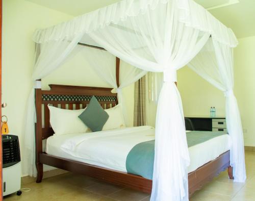 a bedroom with a canopy bed with white curtains at Harry's Kisumu Oasis in Kisumu