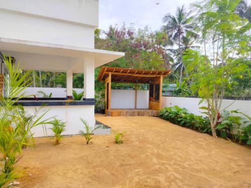 una casa blanca con un pabellón en un patio en Tropical oasis en Thiruvananthapuram