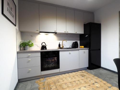 a kitchen with white cabinets and a black refrigerator at Mokre 22 in Bielsk Podlaski