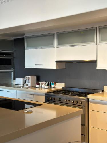 uma cozinha com armários brancos e um forno com placa de fogão em The Atlantic DonReal Guesthouse na Cidade do Cabo