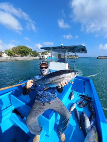 a man sitting on a boat holding a fish at Endhaa, Divers Home in Fuvahmulah