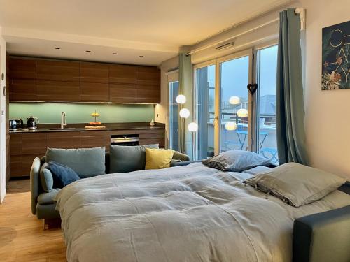 a bedroom with a large bed and a couch at Le reflet de la Seine - balcon - 2 chambres - RER A in Carrières-sous-Poissy