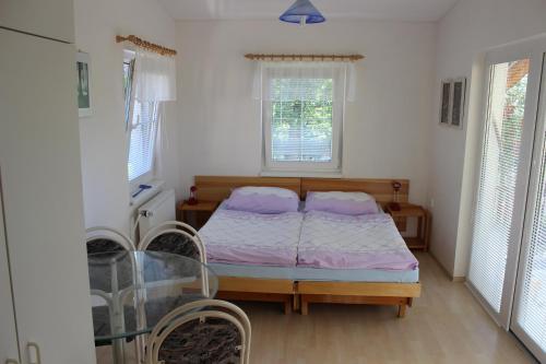 a bedroom with a bed and two windows at Penzion Gomelská in Horní Stropnice