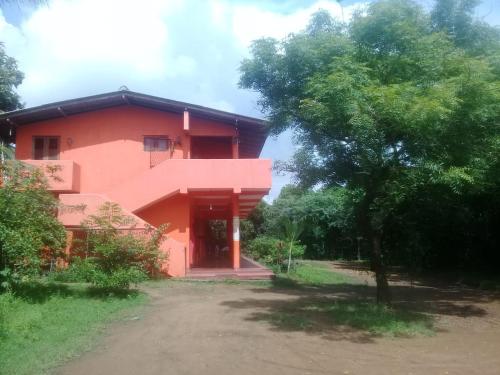 a red building with a tree in front of it at Sayonara Resort in Hambantota