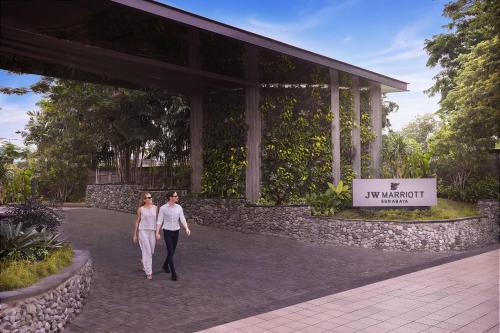 a man and woman walking in front of a building at JW Marriott Hotel Surabaya in Surabaya