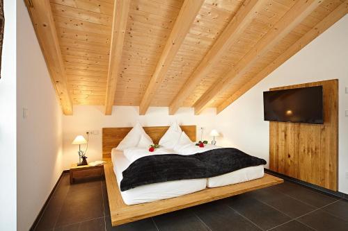 a bedroom with a large bed and a flat screen tv at Hirschbergblick - fewo-badhindelang in Bad Hindelang