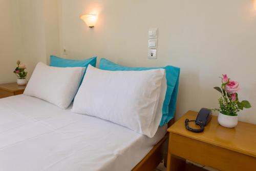 a bed with white pillows and a phone on a table at Laganas Holidays Hotel in Laganas